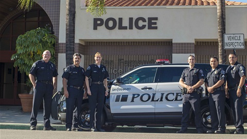 Police officers posing for photo in front of police cruiser