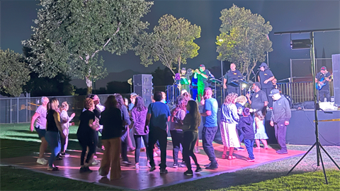 Concert at the park photo of people dancing with band playing on stage