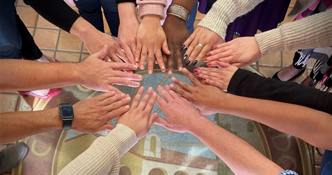 Photo of hands in a circle above the City Seal